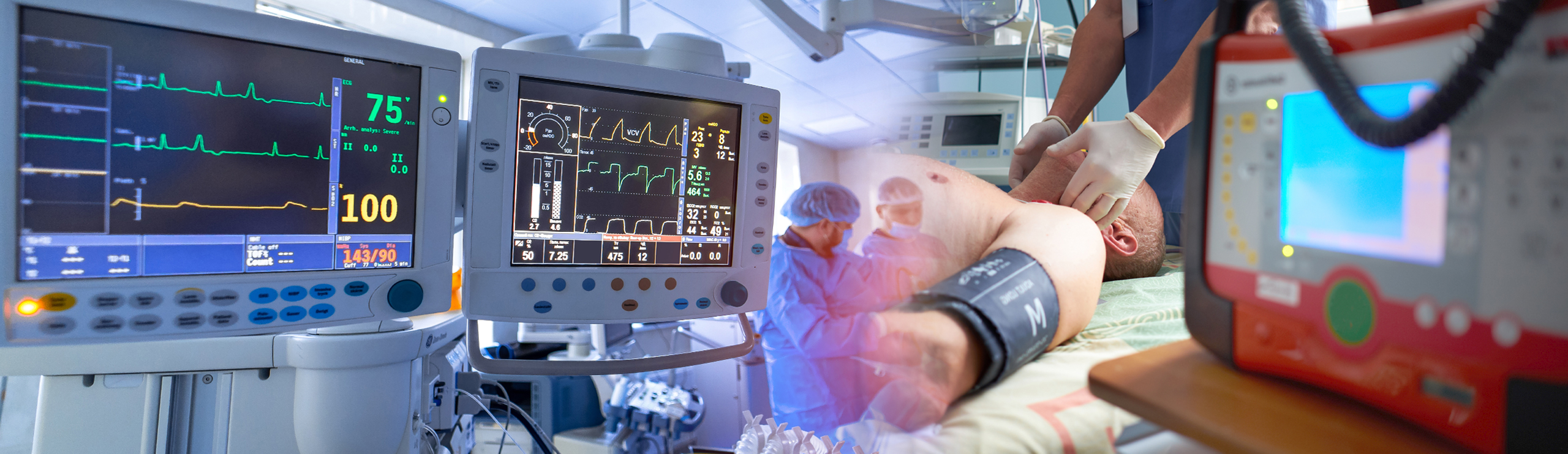 Intensivstation mit medizinischen Monitoren und Pflegepersonal, das einen Patienten mit Blutdruckmanschette behandelt, am rechten Bildrand ein Defibrillator