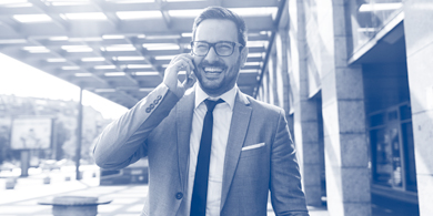 lächelnder Geschäftsmann am Mobiltelefon vor Klinik