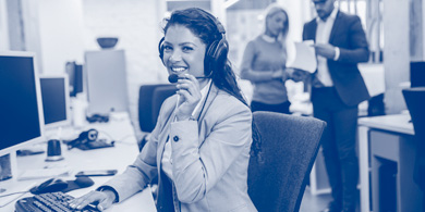 Junge Frau telefoniert am Computer sitzend mit Headset