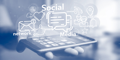 auf einer flach ausgestreckten Hand liegt ein Mobiltelefon, über dessen Bildschirm in einer Wolke Symbole und Wörter rund um das Thema social media schweben