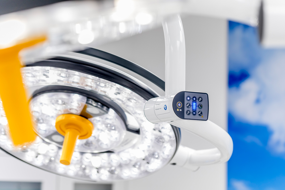 Moderne Operationsleuchte mit LED-Lichtring und digitalem Bedienfeld an einem weißen Arm
